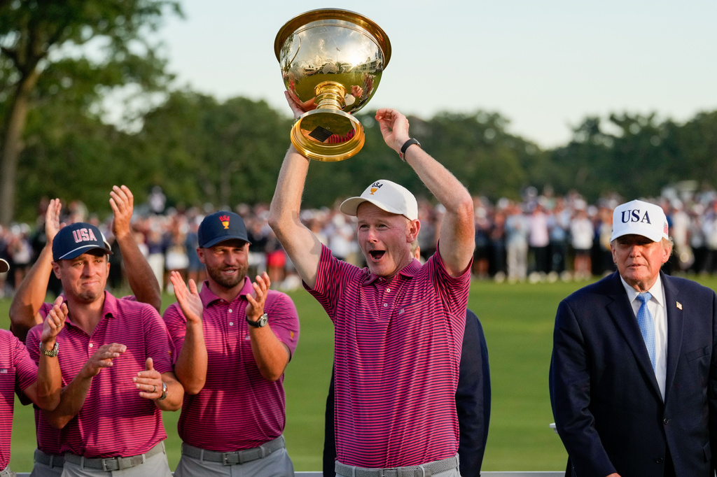 President Donald Trump, right, watches as USA team captain Brandt Snedeker holds the Presidents Cup trophy after the Presidents Cup golf tournament against the International team at Medinah Country Club, Sunday, Sept. 27, 2026, in Medinah, Ill. (AP Photo/Chris Carlson)