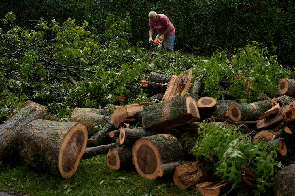Jim Koehler works with a chain saw to remove an oak tree damaged by severe storms on Tuesday, in his daughter's front yard in Cincinnati on Wednesday, Aug. 12, 2026. (AP Photo/Carolyn Kaster)