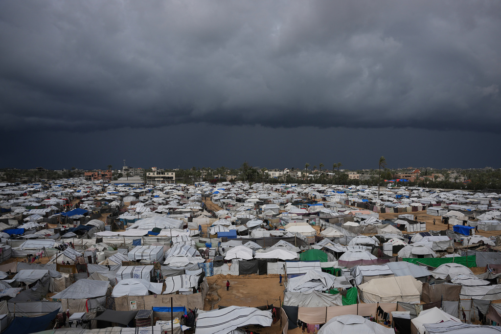 Palestinian children stand on an area surrounded by makeshift tents in a camp for displaced people in Deir al-Balah, central Gaza Strip, Saturday, Dec. 27, 2025. (AP Photo/Abdel Kareem Hana)