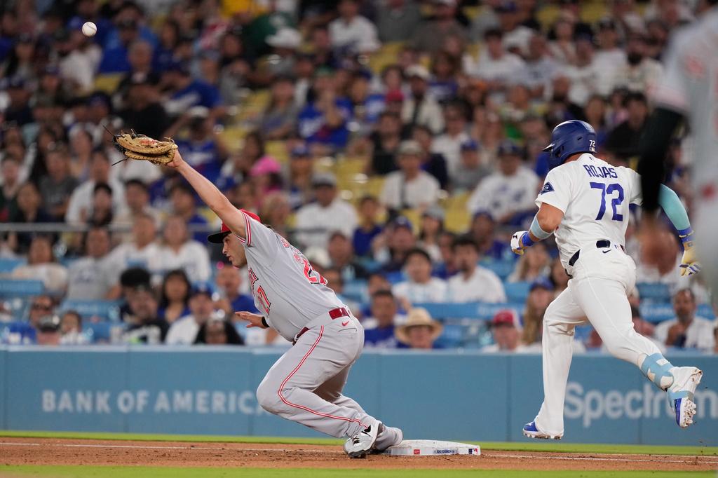 Los Angeles Dodgers' Miguel Rojas, right, makes it to first as Cincinnati Reds first baseman Sal Stewart misses the ball on a throwing error that allowed two runs to score during the fifth inning of a baseball game Monday, Sept. 7, 2026, in Los Angeles. (AP Photo/Mark J. Terrill)