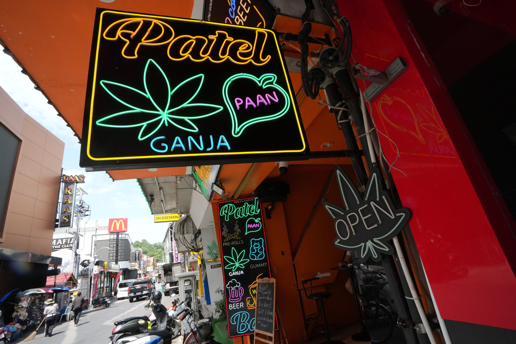 Workers clean a road next to a sign of a cannabis shop in Pattaya, Thailand, Tuesday, Sept. 1, 2026. (AP Photo/Sakchai Lalit)