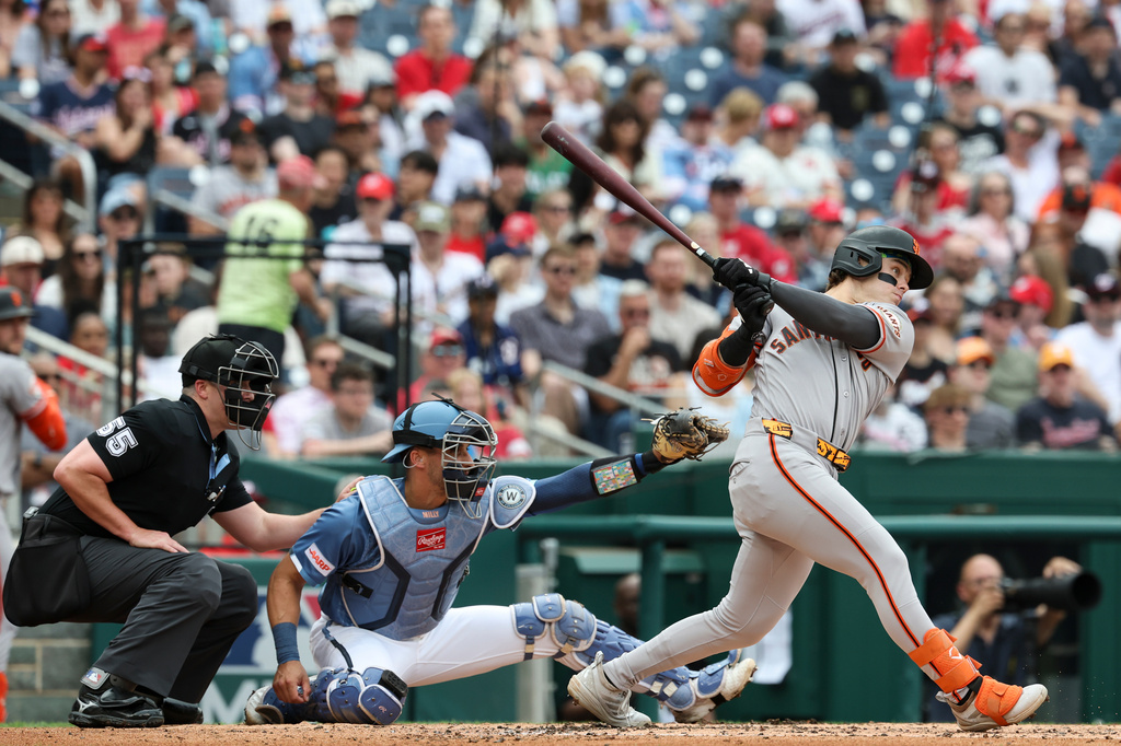 San Francisco Giants' Drew Gilbert, right, follows through on his swing after hitting a single off Washington Nationals pitcher Cade Cavalli (not shown) which scored Giants' Heliot Ramos during the second inning of a baseball game, Saturday, April 18, 2026, in Washington. (AP Photo/Terrance Williams)