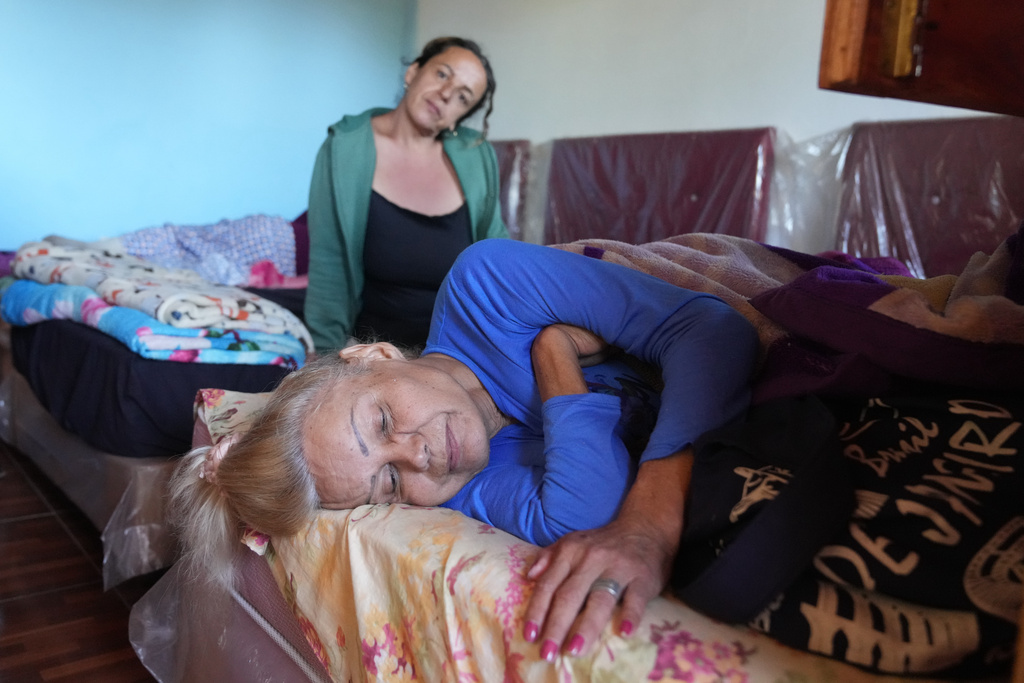 Brenda Gimenez accompanies Liz Paola Cortaza, front, as she recovers from the flu at Casa Diversa in Augusto Saldivar, Paraguay, Friday, July 25, 2025. (AP Photo/Jorge Saenz)
