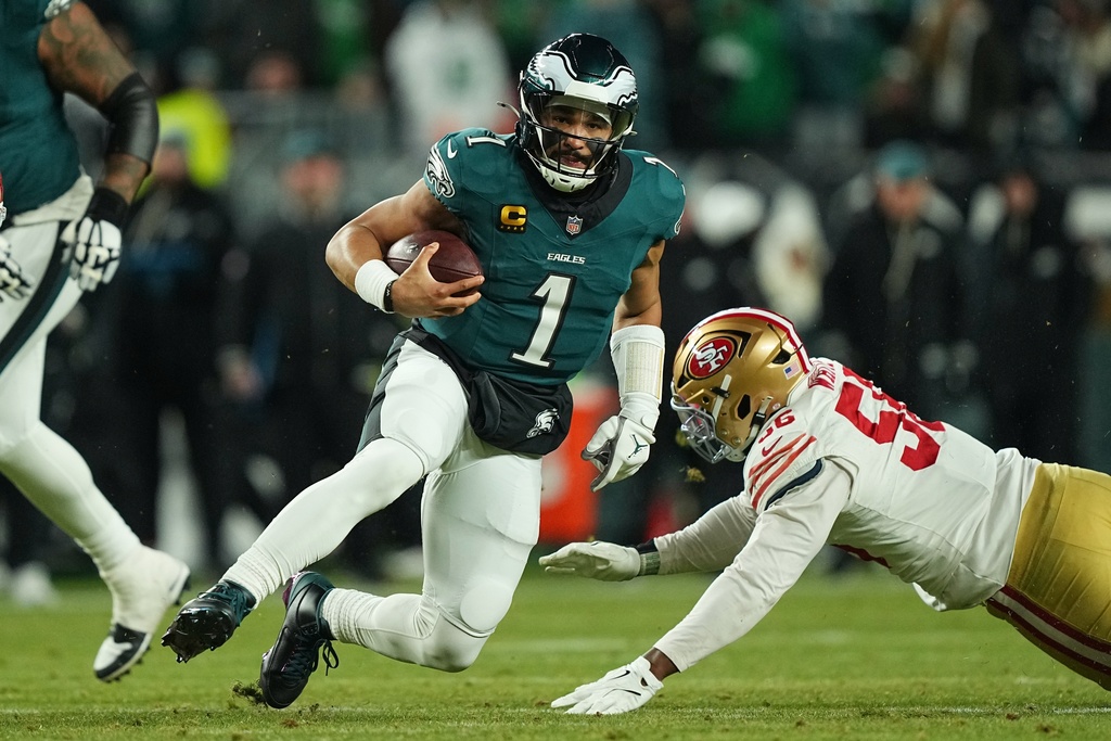 Philadelphia Eagles quarterback Jalen Hurts (1) runs with the ball as San Francisco 49ers defensive end Keion White (56) tries to stop him during the second half of an NFL wild-card playoff football game Sunday, Jan. 11, 2026, in Philadelphia. (AP Photo/Matt Rourke)