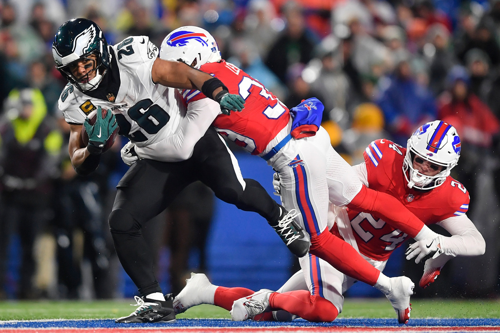 Philadelphia Eagles' Saquon Barkley, left, is tackled by Buffalo Bills' Cam Lewis, center, and Cole Bishop during the first half of an NFL football game, Sunday, Dec. 28, 2025, in Buffalo, N.Y. (AP Photo/Adrian Kraus)