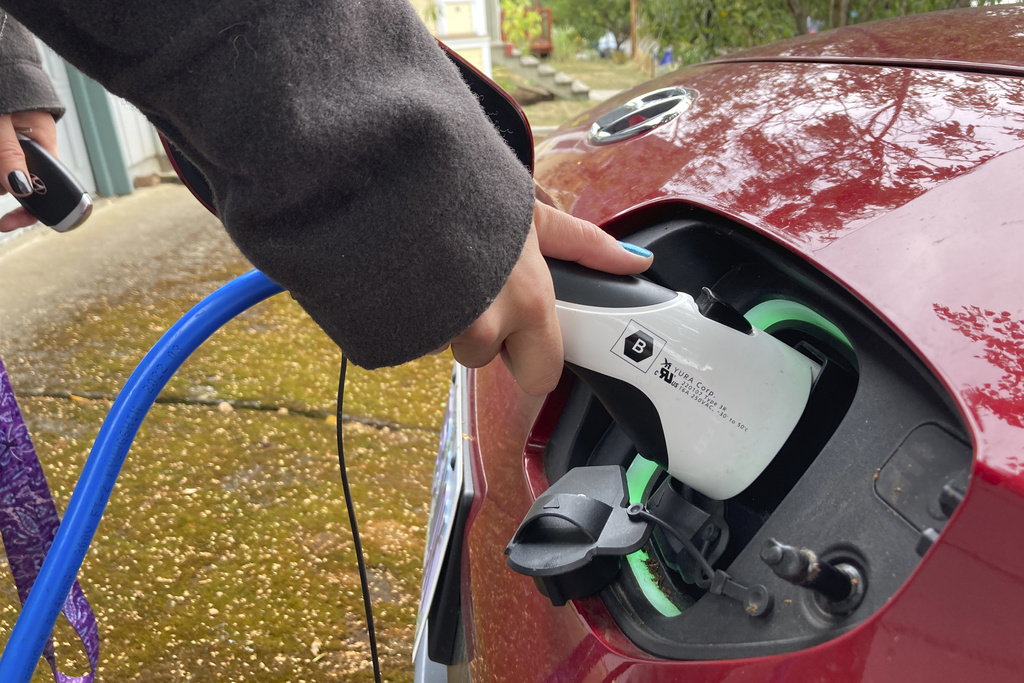 FILE - Rebecca DeWhitt charges her electric vehicle on Sept. 30, 2022, in the driveway of the Portland, Ore., home she rents. (AP Photo/Gillian Flaccus, File)