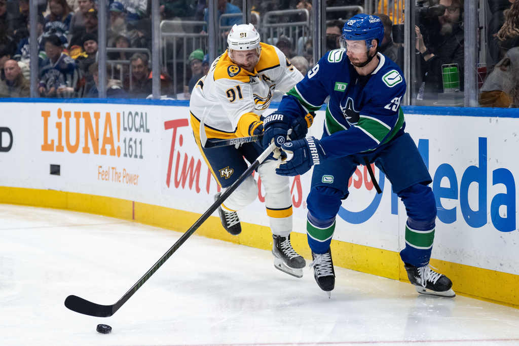 Nashville Predators' Steven Stamkos (91) and Vancouver Canucks' Marcus Pettersson (29) vie for the puck during the first period of an NHL game in Vancouver, on Thursday, March 12, 2026. (Ethan Cairns/The Canadian Press via AP)
