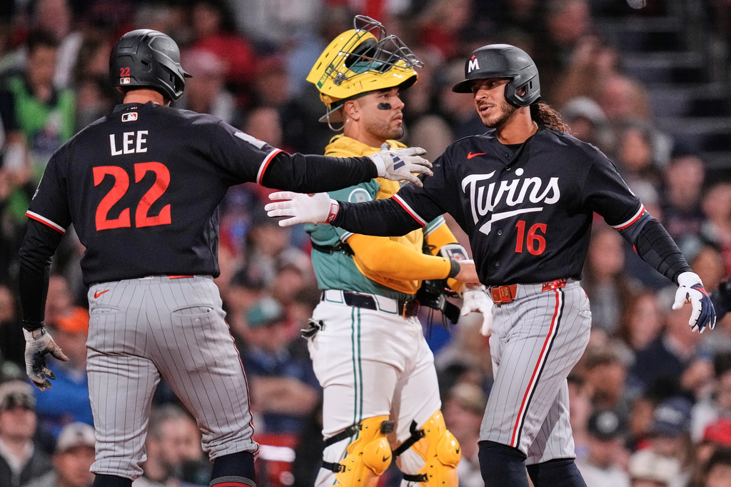 Minnesota Twins' Austin Martin (16) is congratulated by Brooks Lee (22) after his two-run home run, as Boston Red Sox catcher Carlos Narváez waits for play to continue, during the seventh inning of a baseball game against the Boston Red Sox, Friday, May 22, 2026, in Boston. (AP Photo/Charles Krupa)