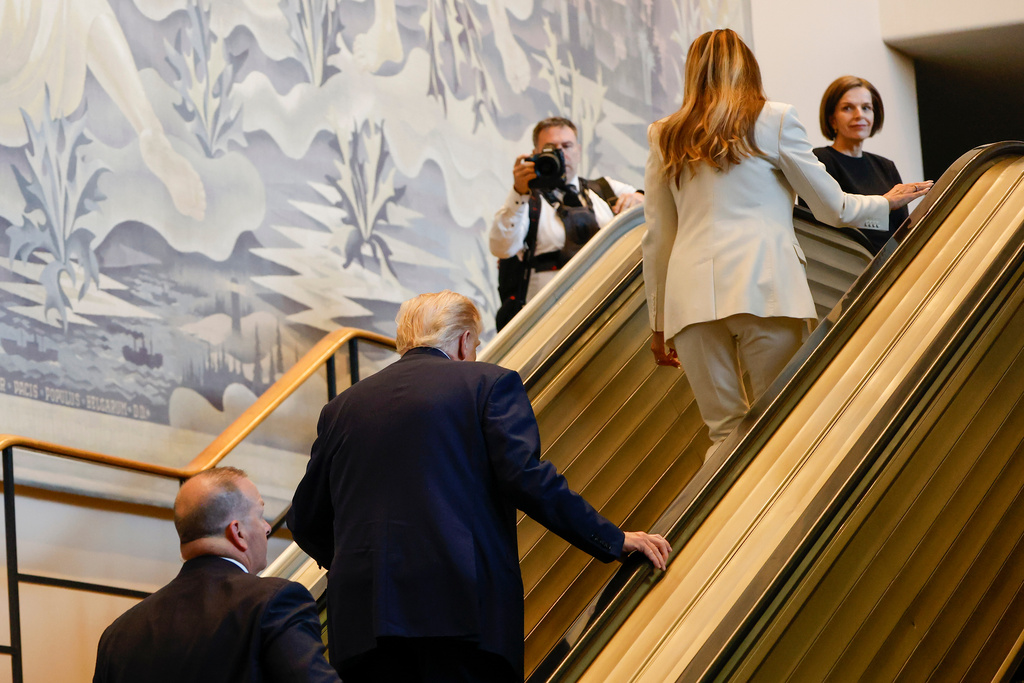President Donald Trump, center, and First Lady Melania Trump, upper right, walk up the escalator after it stalled as he rode up to the General Assembly Hall, Tuesday, Sept. 23, 2025, at U.N. headquarters. (AP Photo/Stefan Jeremiah)