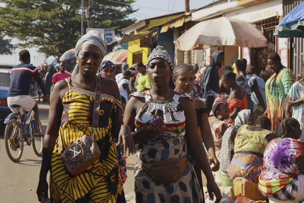 Women walk past people shopping at a market in Bissau, Guinea-Bissau, Friday, Nov. 28, 2025. (AP Photo/Darcicio Barbosa)