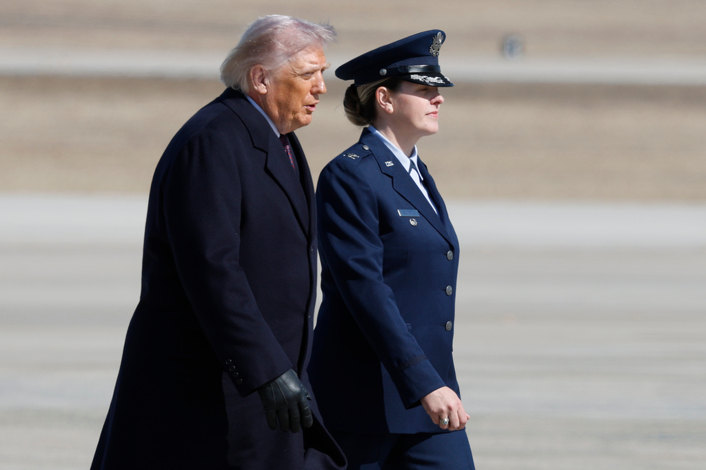 President Donald Trump, left, is escorted by Air Force 89th Air Wing Deputy Commander Melissa Dombrock, right, before boarding Air Force One, Friday, Feb. 27, 2025, at Joint Base Andrews, Md. (AP Photo/Luis M. Alvarez)