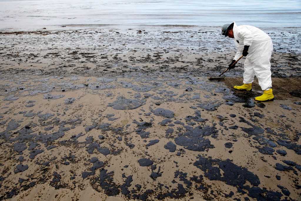 FILE - A worker removes oil from the sand at Refugio State Beach, north of Goleta, Calif., May 21, 2015. (AP Photo/Jae C. Hong, File)