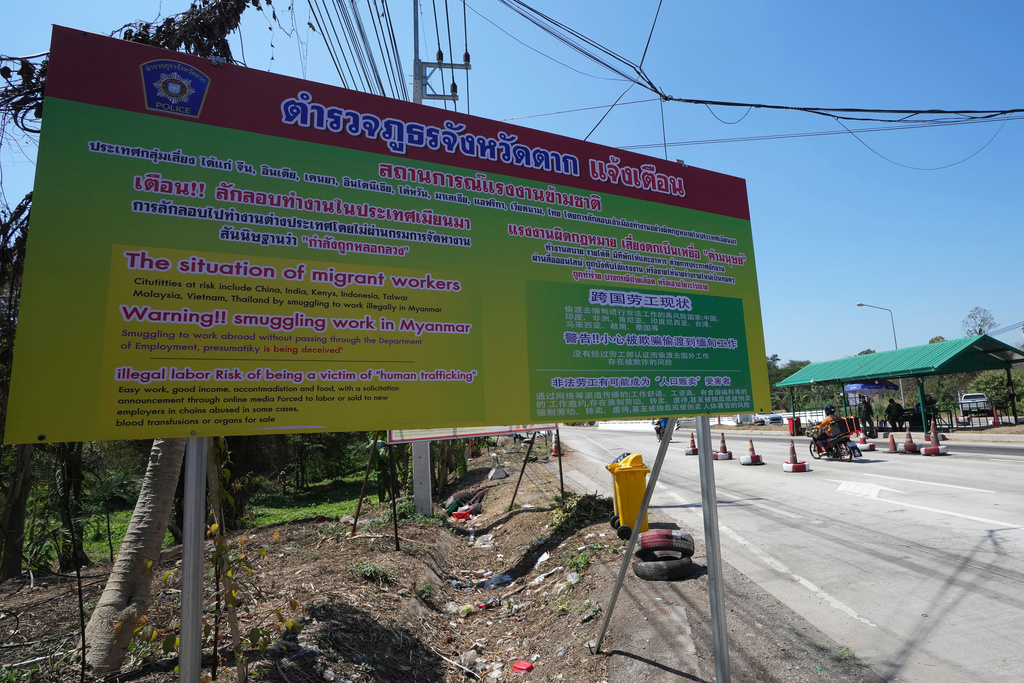 FILE - A sign near military checkpoint warns in Thai, English and Chinese of the danger of being trafficked and forced to work in locked scam compounds across the Myanmar border, in Mae Sot, Thailand, Feb. 26, 2025. (AP Photo/Sakchai Lalit, File)