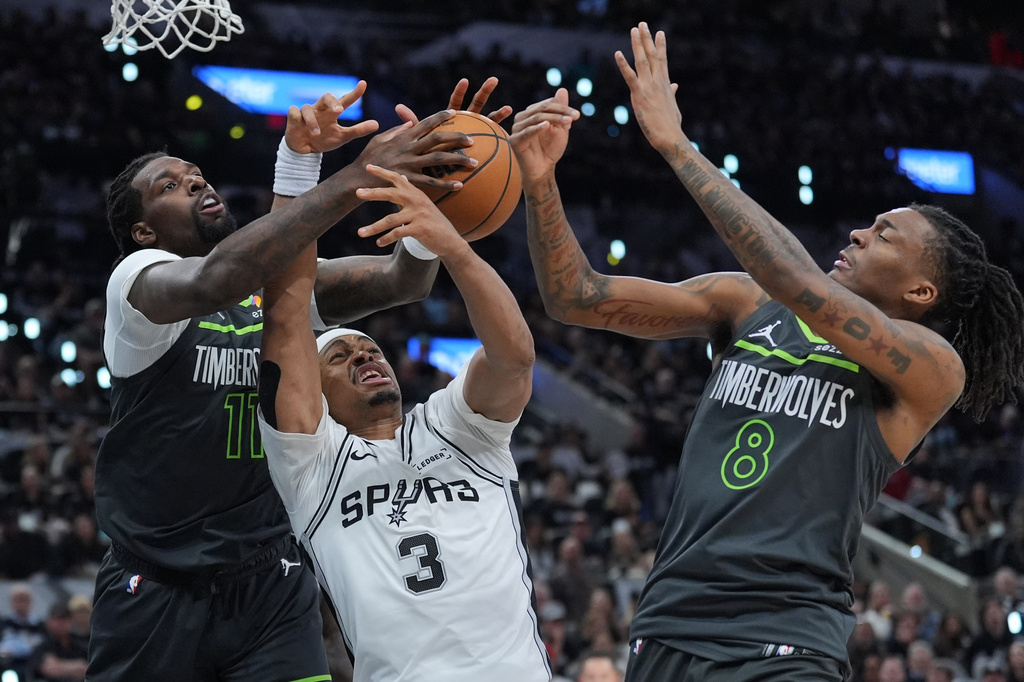 San Antonio Spurs forward Keldon Johnson (3) battles Minnesota Timberwolves center Naz Reid (11) and guard Bones Hyland (8) for a rebound during the second half in Game 2 of a second-round NBA playoffs basketball series in San Antonio, Wednesday, May 6, 2026. (AP Photo/Eric Gay)