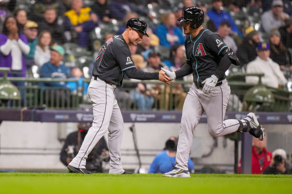 Arizona Diamondbacks' Nolan Arenado rounds the bases on a two-run homer with a shake from third base coach J.R. House during the fourth inning of a baseball game against the Milwaukee Brewers Wednesday, April 29, 2026, in Milwaukee. (AP Photo/Andy Manis)
