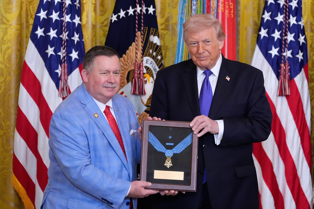 Chris Edmonds, left, son of Master Sergeant Roderick Edmonds, with President Donald Trump, is presented the Medal of Honor on behalf of his father, during a ceremony in the East Room of the White House, Monday, March 2, 2026, in Washington. (AP Photo/Alex Brandon)