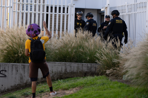 A protester waves to Department of Homeland Security officials as they walk to the gates of the U.S. Immigration and Customs Enforcement facility after inspecting an area outside on Sunday, Sept. 28, 2025, in Portland, Ore. (AP Photo/Jenny Kane) A protester waves to Department of Homeland Security officials as they walk to the gates of the U.S. Immigration and Customs Enforcement facility after inspecting an area outside on Sunday, Sept. 28, 2025, in Portland, Ore. (AP Photo/Jenny Kane)