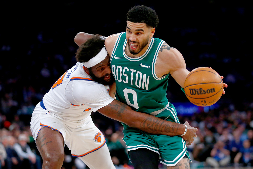 New York Knicks center Mitchell Robinson, left, defends Boston Celtics guard Jayson Tatum during the second half of an NBA basketball game Thursday, April 9, 2026, in New York. (AP Photo/John Munson)