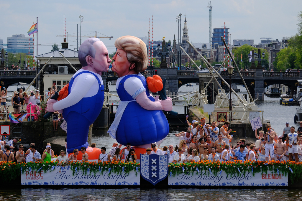 Two inflatable caricature balloons depicting U.S. President Donald Trump, center, and Russian President Vladimir Putin, left, as people line the Dutch capital's historic canals Saturday, Aug. 1, 2026, to watch the Amsterdam Pride Canal Parade. (AP Photo/Patrick Post)