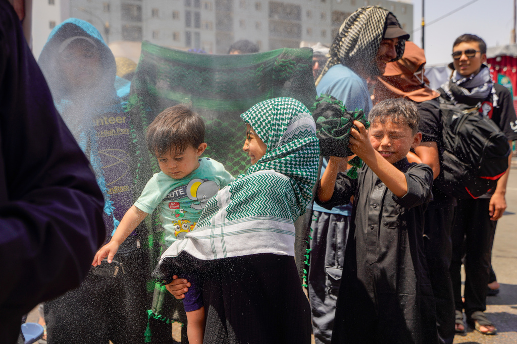 Water is sprayed over Shiite pilgrims to cool them as they make their way to Karbala for Arbaeen, the annual Shiite commemoration marking 40 days after Ashura, in Najaf, Iraq, Friday, July 31, 2026. (AP Photo/Ammar Khalil)