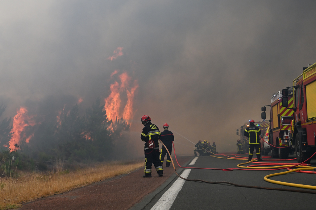 Firefighters spray water in a burning forest near Lacanau, southwestern France, Saturday, July 25, 2026. (AP Photo/Emma Da Silva)