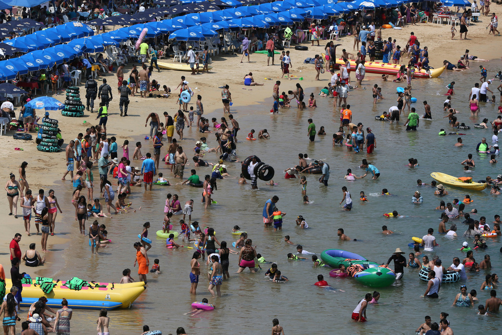FILE - Residents and visitors wade in the waters of Caletilla beach in Acapulco, Mexico, May 13, 2016. (AP Photo/Enric Marti, File)