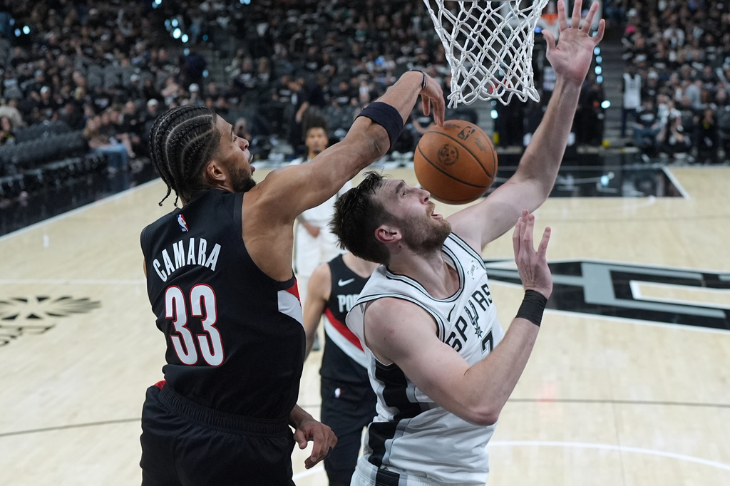 San Antonio Spurs center Luke Kornet (7) is blocked by Portland Trail Blazers forward Toumani Camara (33) during the second half in Game 2 of a first-round NBA playoffs basketball series in San Antonio, Tuesday, April 21, 2026. (AP Photo/Eric Gay)