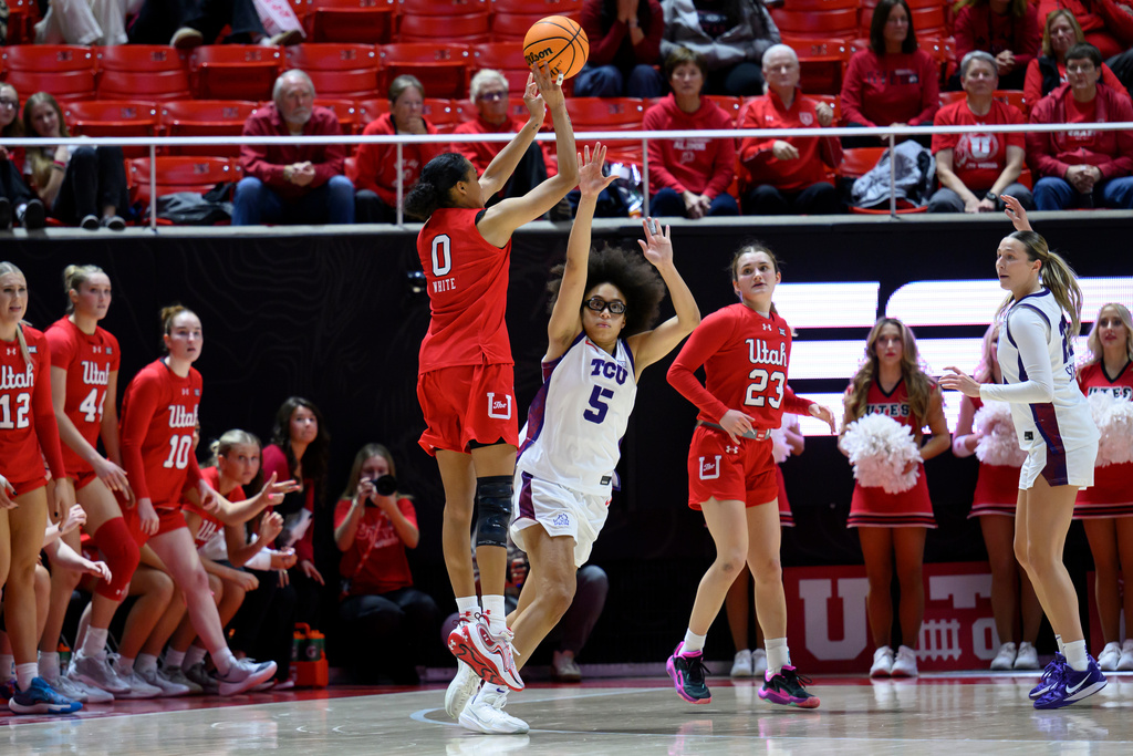 Utah guard Lani White (0) shoots to make a tying 3-point basket over TCU guard Olivia Miles (5) to send the game to overtime during the second half of an NCAA college basketball game, Saturday, Jan. 3, 2026, in Salt Lake City. (AP Photo/Tyler Tate)