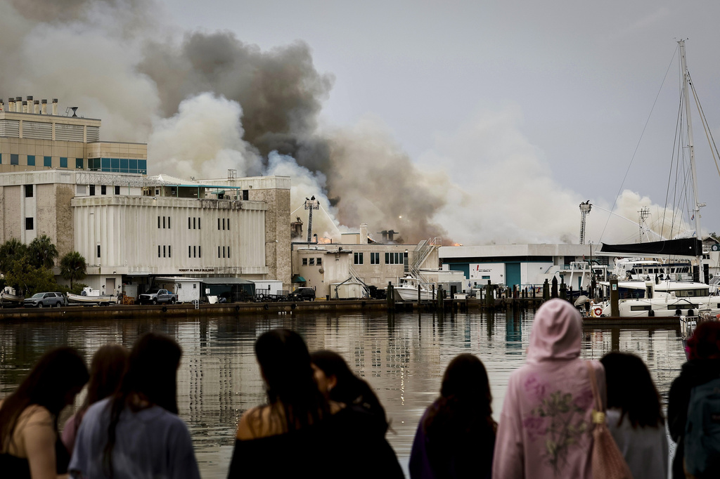 Onlookers watch as firefighters work to extinguish a fire at the University of South Florida campus Saturday, May 2, 2026, in St. Petersburg, Fla. (Luis Santana/Tampa Bay Times via AP)
