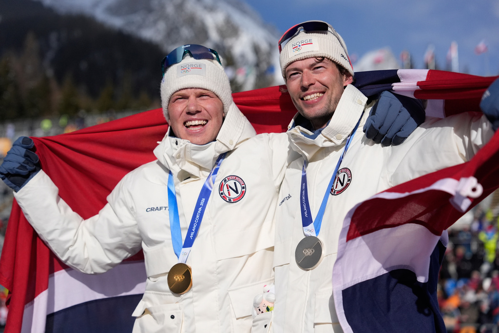 Gold medalist Johannes Dale-Skjevdal, of Norway, left, and silver medalist Sturla Holm Laegreid, of Norway, pose for photos after the men's 15-kilometer mass start biathlon race at the 2026 Winter Olympics in Anterselva, Italy, Friday, Feb. 20, 2026. (AP Photo/Mosa'ab Elshamy)