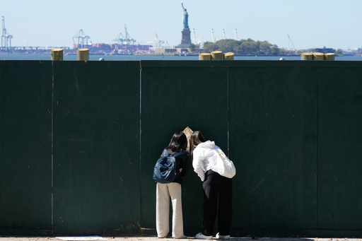 People look through fence to get a glance at the Statue of Liberty in New York, Wednesday, Oct. 1, 2025. (AP Photo/Seth Wenig) People look through fence to get a glance at the Statue of Liberty in New York, Wednesday, Oct. 1, 2025. (AP Photo/Seth Wenig)