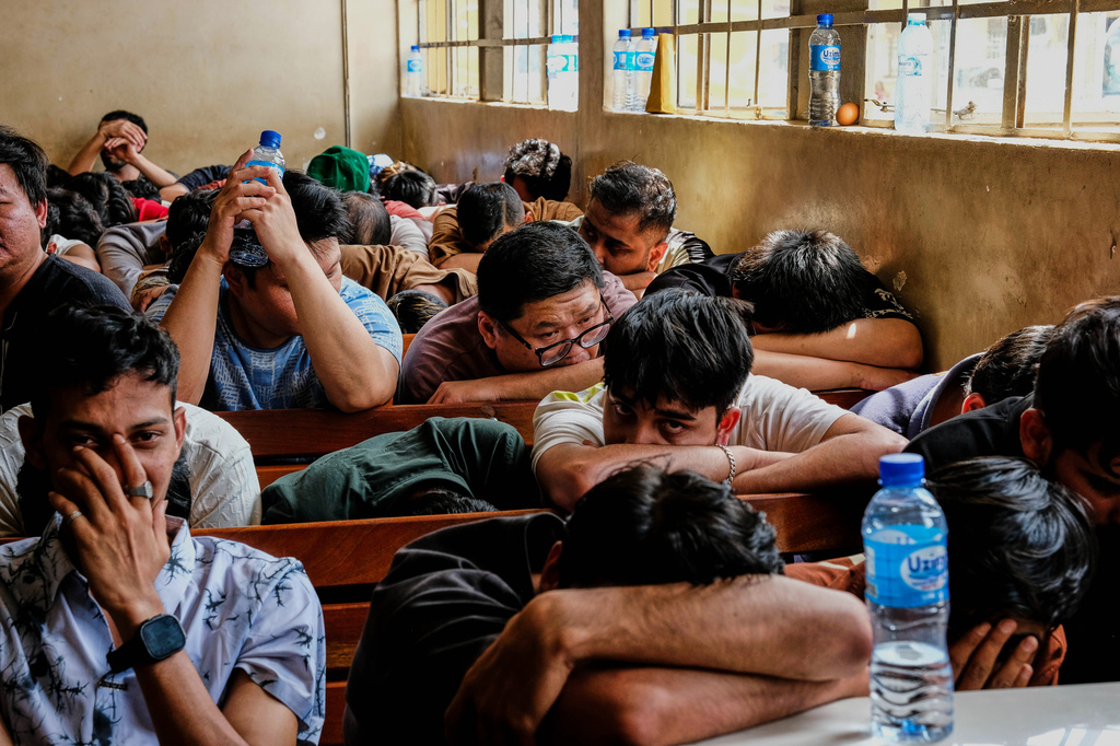 Detainees sit in a room after Ugandan authorities arrested dozens of foreigners in a crackdown on illegal migration in Kampala, Uganda, Tuesday, April 28, 2026. (AP Photo/Hajarah Nalwadda)