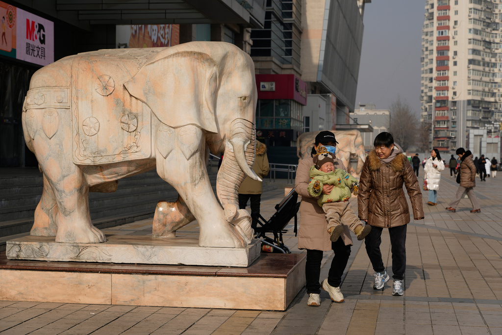 A woman lifts up a child in Beijing, China, on Jan. 15, 2026. (AP Photo/Ng Han Guan)