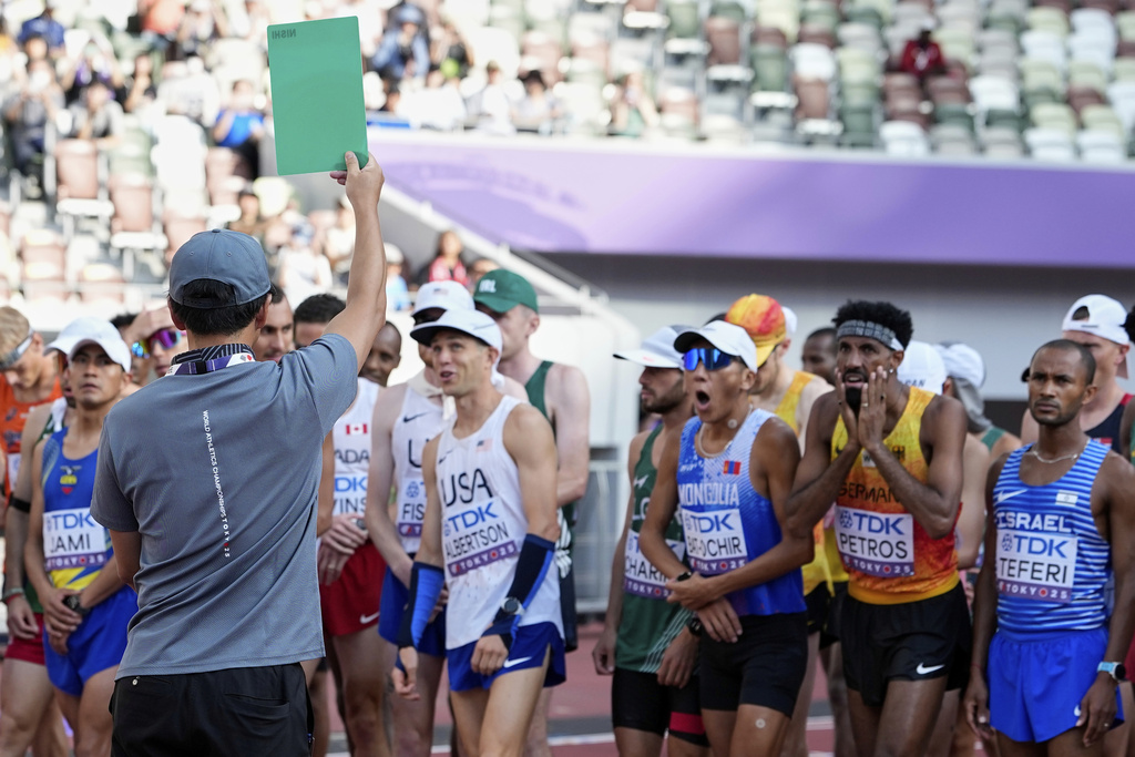 Runners react as an official shows a green card after a false start in the men's marathon at the World Athletics Championships in Tokyo, Monday, Sept. 15, 2025. (AP Photo/Ashley Landis)