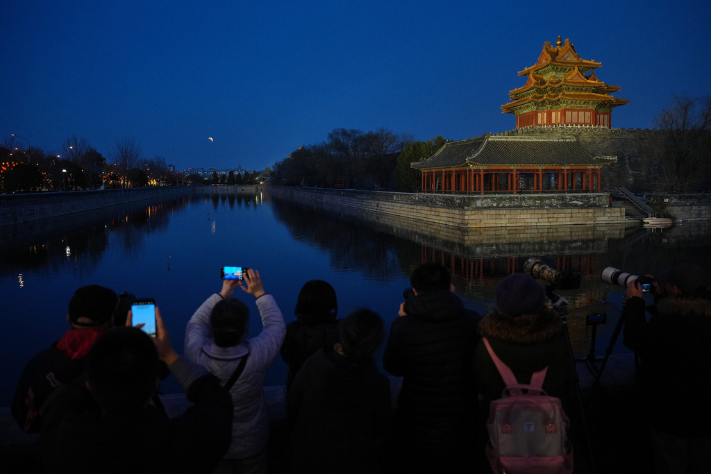 People film the lunar eclipse near the Forbidden City in Beijing, China, Tuesday, March 3, 2026. (AP Photo/Andy Wong)