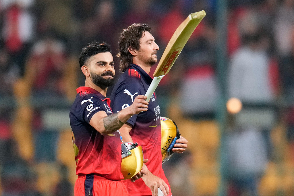 Royal Challengers Bengaluru's Virat Kohli, left, gestures to the fans as he walks out with teammate Tim David after winning the Indian Premier League cricket match against Sunrisers Hyderabad in Bengaluru, India, Saturday, March 28, 2026. (AP Photo/Aijaz Rahi)