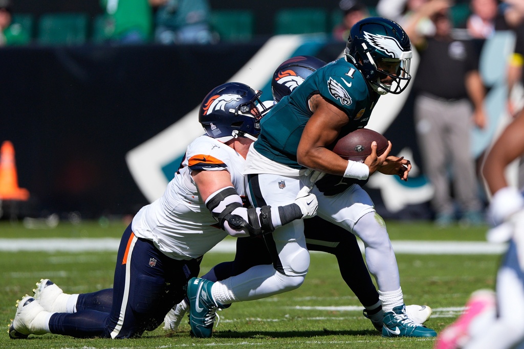 Denver Broncos linebacker Nik Bonitto and Broncos defensive end Zach Allen, left, bring down Philadelphia Eagles quarterback Jalen Hurts (1) during the first half of an NFL football game Sunday, Oct. 5, 2025, in Philadelphia. (AP Photo/Chris Szagola)