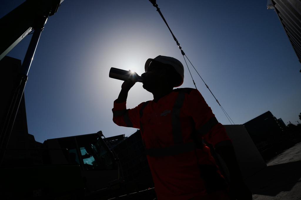 A worker drinks water on a construction site during high temperatures in Boulogne Billancourt, outside Paris, Wednesday, June 24, 2026. (AP Photo/Christophe Ena )