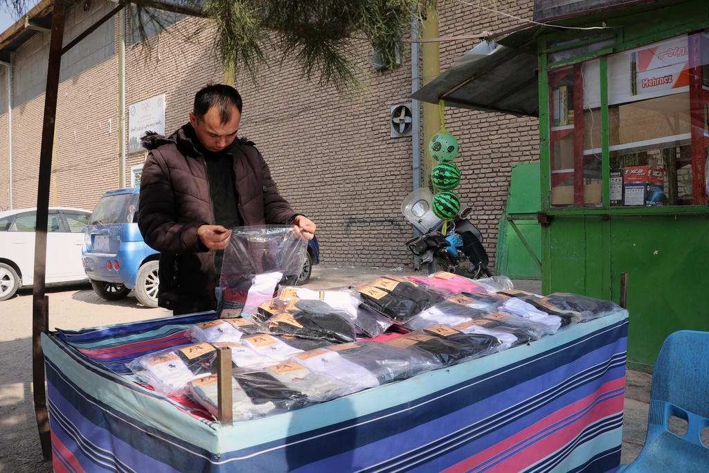 Mohammad Arif Jafari, 40, prepares his stall to sell socks made in a workshop staffed entirely by men with disabilities, in Herat, western Afghanistan, Monday, Dec. 8, 2025. (AP Photo/Omid Haqjoo)