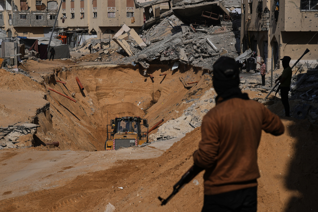 Members of the Hamas militant group search underground for the bodies of Israeli hostages amid destroyed buildings in Khan Younis, in the southern Gaza Strip, Sunday, Oct. 19, 2025. (AP Photo/Abdel Kareem Hana)