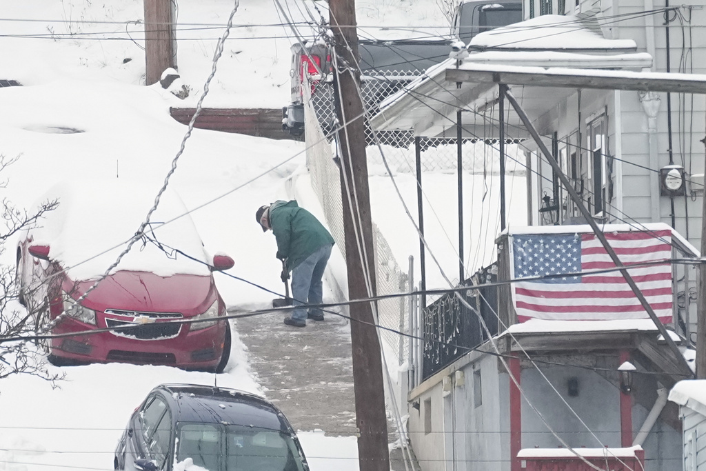 A person shovels a sidewalk after a winter snow storm in Pottsville, Pa., Tuesday, Dec. 2, 2025. (AP Photo/Matt Rourke)