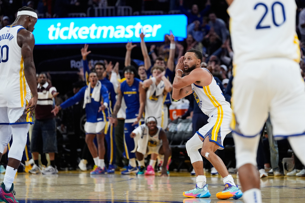 Golden State Warriors guard Stephen Curry (30) gestures toward forward Jimmy Butler III, left, who scored a 3-point basket, during overtime of an NBA basketball game against the Denver Nuggets, Thursday, Oct. 23, 2025, in San Francisco. (AP Photo/Godofredo A. Vásquez)