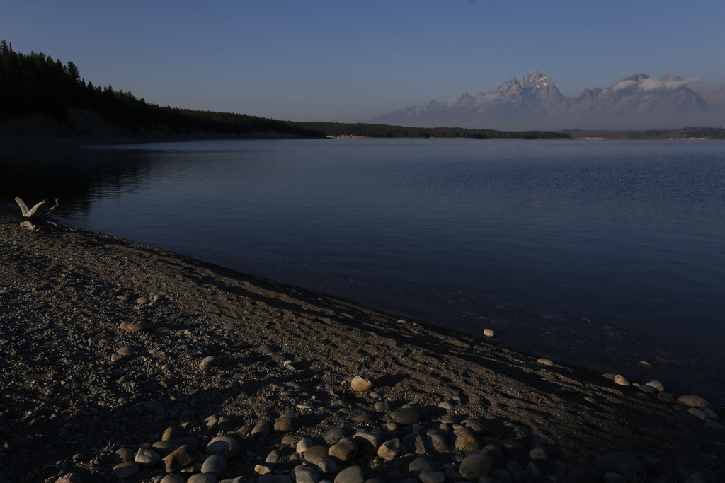 FILE - The sun at dawn illuminates mountain peaks as seen from the shore of Jackson Lake in Grand Teton National Park, Wyo., Thursday, Aug 25, 2016. (AP Photo/Brennan Linsley, File)