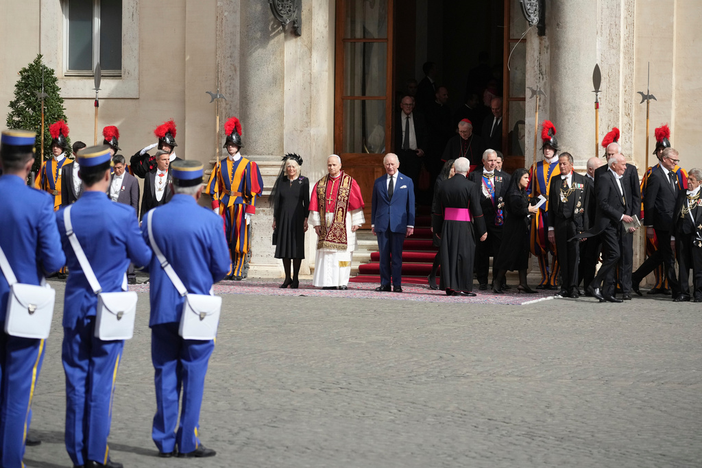Pope Leo XIV, center, is flanked by Britain's King Charles III and Queen Camilla in the St. Damasus Courtyard at the Vatican after a state visit and pray with him in the Sistine Chapel, Thursday, Oct. 23, 2025. (AP Photo/Andrew Medichini)