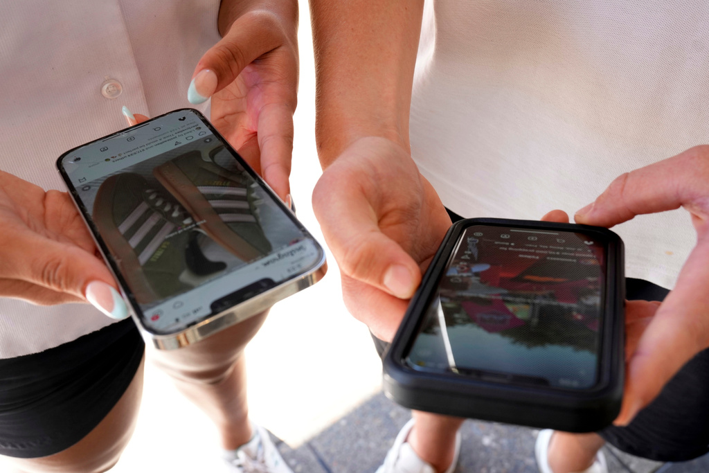 FILE - Young persons use their phones to view social media in Sydney, on Nov. 8, 2024. (AP Photo/Rick Rycroft, File)