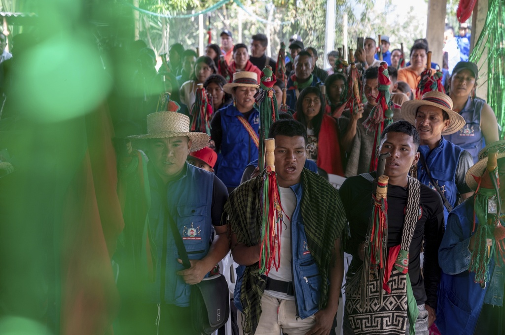 As a graduation ceremony begins, participants stand to honor the Nasa Indigenous and Indigenous guard anthems July 18, 2025, in Manuelico village, Caldono, Colombia. (AP Photo/Nadège Mazars)