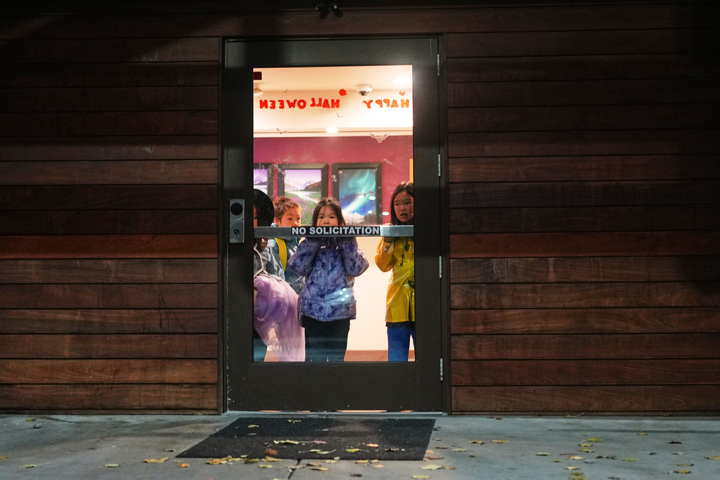 Evacuee children displaced by ex-Typhoon Halong wait in the lobby of their temporary hotel housing for a bus to take them to College Gate Elementary, where students spend half their time learning in Yup'ik language immersion, Friday, Oct. 31, 2025, in Anchorage, Alaska. (AP Photo/Lindsey Wasson)