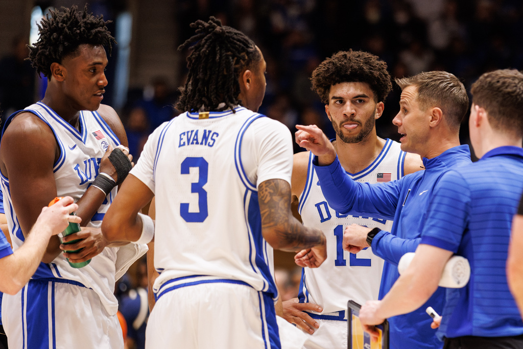 Duke head coach Jon Scheyer, right, speaks to Duke's Cameron Boozer, third from right, Isaiah Evans (3), and Patrick Ngongba II, left, during a timeout in an NCAA college basketball game against Georgia Tech in Durham, N.C., Wednesday, Dec. 31, 2025. (AP Photo/Ben McKeown)
