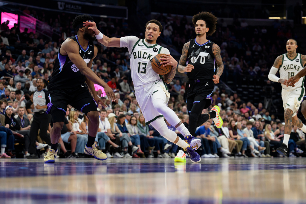 Milwaukee Bucks guard Ryan Rollins (13) drives to the basket while guarded by Utah Jazz guard Elijah Harkless, left, during the first half of an NBA basketball game Thursday, March 19, 2026, in Salt Lake City. (AP Photo/Tyler Tate)