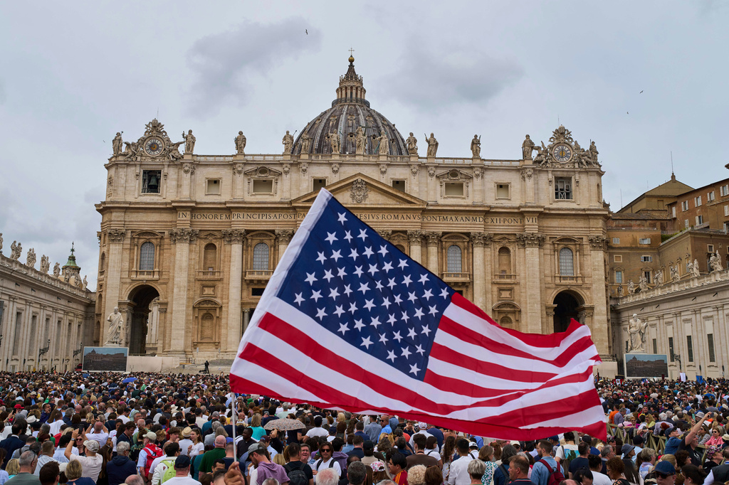 FILE - A flag from the United States waves in the crowd as Pope Leo XIV appears at the central balcony of St. Peter's Basilica for his first Sunday blessing after his election, in St. Peter's Square at the Vatican, Sunday, May 11, 2025. (AP Photo/Bernat Armangue, File)
